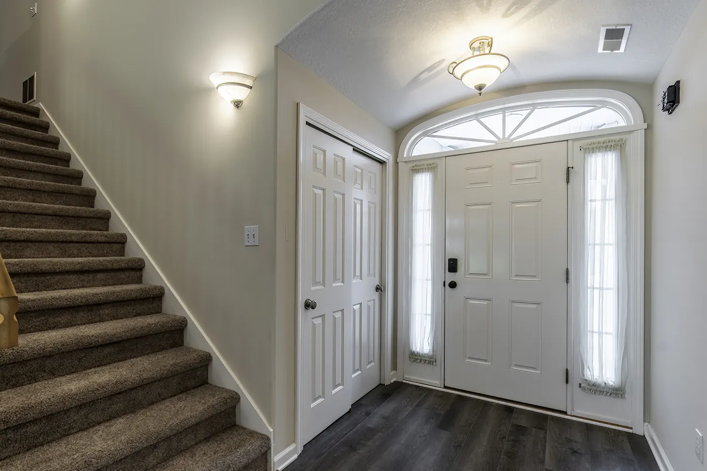 Interior foyer and staircase at 1906 Kelleys Landing, Fort Wayne IN with white entry door and sidelights